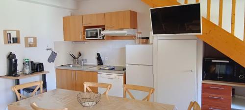 a small kitchen with a table and a refrigerator at LUZVAL Duplex avec Balcon in Luz-Saint-Sauveur