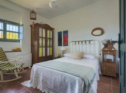 a bedroom with a white bed and a chair at Finca Olivo Llorón in Montilla