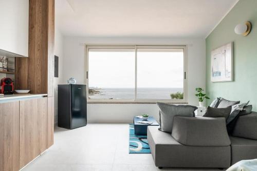 a living room with a couch and a large window at Nel Blu Dipinto Di Blu in Simius