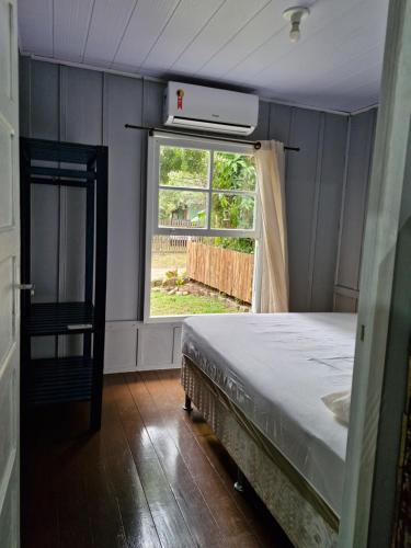 a bedroom with a bed and a window at Casinha Trilha da Guarda in Guarda do Embaú