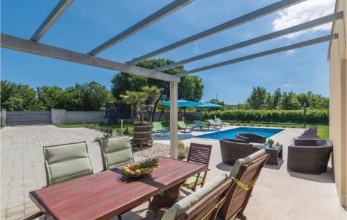a patio with a wooden table and chairs and a pool at Stunning Home In Bale in Bale