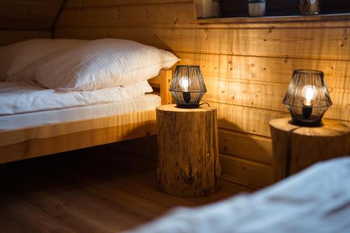 two lamps on wooden posts next to a bed at Niedźwiedzia Dolina in Przybyszów