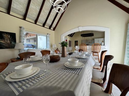 a dining room with a table with plates and wine glasses at Private villa with large pool & 5min walk to beach in Cap Estate