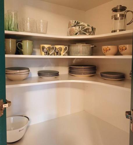 a shelf with plates and cups and dishes on it at Tahunanui holiday apartment in Nelson