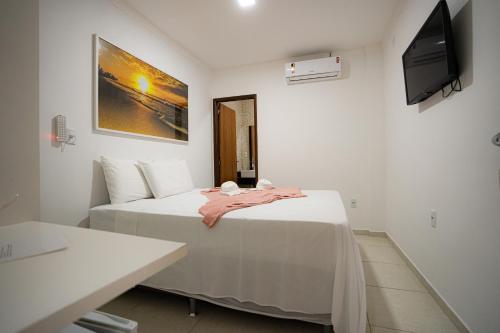 Cette chambre blanche dispose d'un lit et d'une télévision à écran plat. dans l'établissement Pousada Villa Costeira, à Maragogi