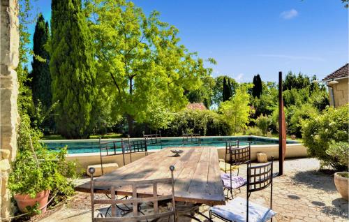 a wooden table and chairs next to a swimming pool at Five Bedroom Gorgeous Home In Tarascon in Tarascon