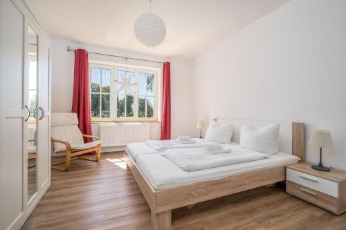 a white bedroom with a large bed and a window at Haus-kl-Mueritz in Rechlin