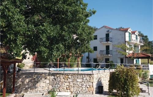 a stone wall with a pool in front of a house at Lovely Home In Podstrana in Podstrana