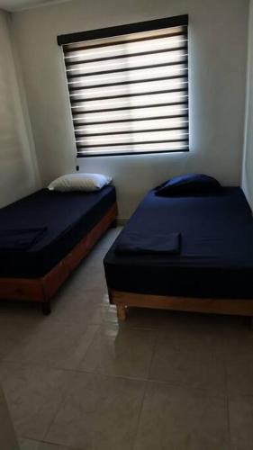two beds sitting in a room with a window at Alojamiento residencial, cerca de TSM in Torreón