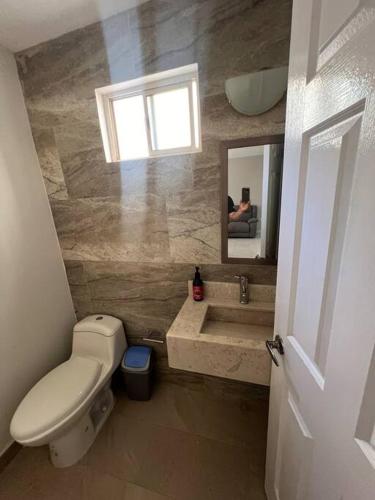 a bathroom with a toilet and a sink and a mirror at Alojamiento residencial, cerca de TSM in Torreón