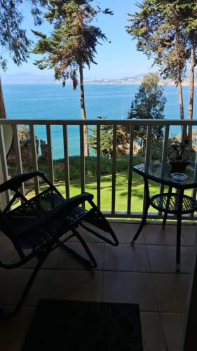 a balcony with a table and a view of the ocean at Bahia Pelícanos Horcón depto. en primera línea in Puchuncaví