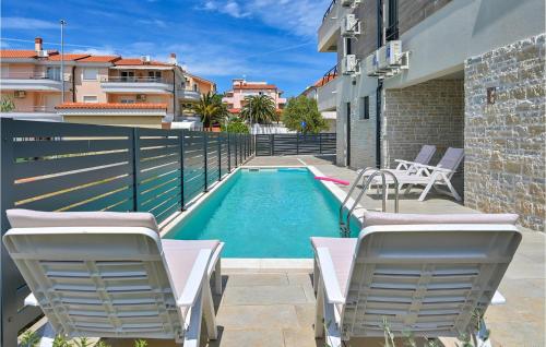 a swimming pool with chairs next to a building at Villa Medulin 1 in Medulin
