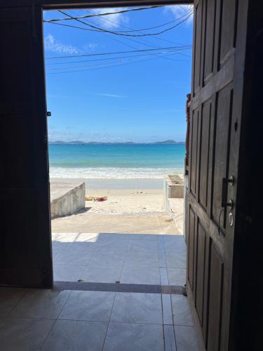an open door to a beach with the ocean at Estalagem pé na areia in Arraial do Cabo