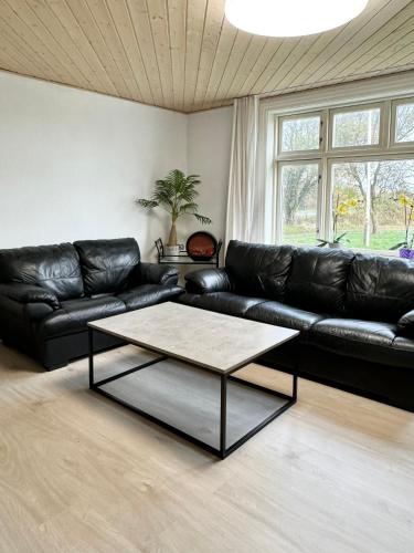 a living room with a black leather couch and a coffee table at BB Esbjerg in Esbjerg