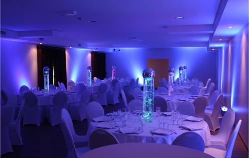 Cette chambre dispose de tables et de chaises blanches avec des lumières violettes. dans l'établissement Nice Apartment In Saint-Affrique, à Saint-Affrique