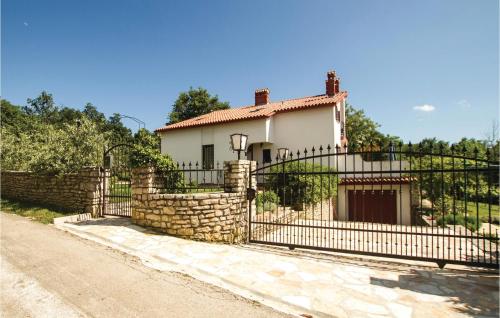 a house with an iron gate and a stone wall at Cozy Home In Kapelica With Wifi in Raša