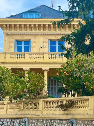 un grand bâtiment jaune avec un balcon et des arbres dans l'établissement Appartement exceptionnel belle époque avec grande terrasse plein sud, à Nice