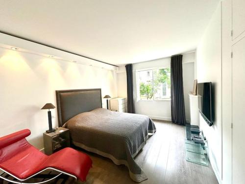 une chambre avec un lit et une chaise rouge dans l'établissement Appartement Victor Hugo, à Paris