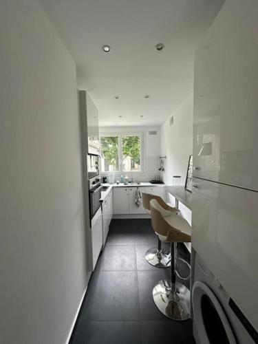 - une cuisine blanche avec un comptoir et des chaises dans l'établissement Appartement Victor Hugo, à Paris