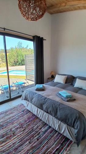 a bedroom with a large bed and a large window at Grado8punto8 Glamping Valle de Los Artistas in Lolol
