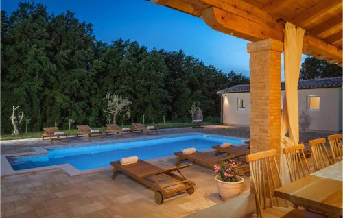 a swimming pool with picnic tables and chairs next to a house at 4 Bedroom Lovely Home In Pusti in Peresiji