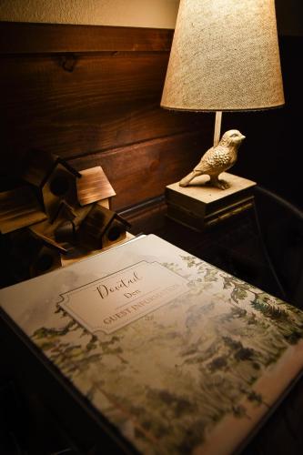 a table with a book and a lamp and a bird statue at Dovetail Den - Tranquil with Hot Tub and Air Conditioning in Ashford
