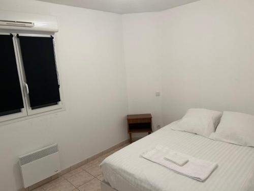 Un dormitorio con una cama blanca con una toalla encima. en La Pause Larzac-Parking privé-A 20 min de Millau, en La Cavalerie