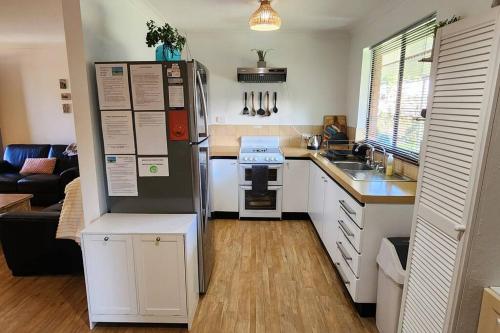a small kitchen with a refrigerator and a stove at Abbey Beach Cottage in Busselton