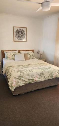 a bedroom with a bed with a flowery comforter at Abbey Beach Cottage in Busselton