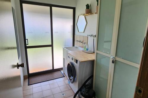 a bathroom with a washing machine and a sink at Abbey Beach Cottage in Busselton