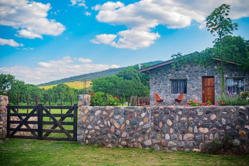 a stone house with a fence and a stone wall at Cabañas 2Tierras in Chicoana