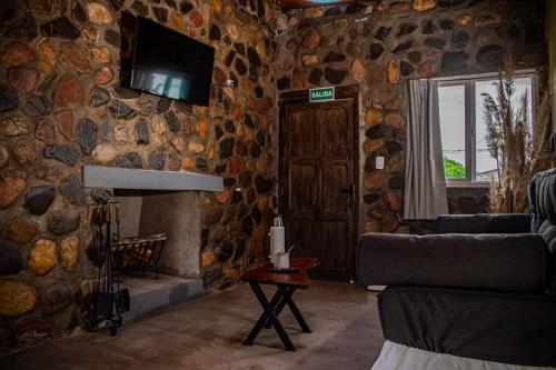 a living room with a stone wall with a couch and a window at Cabañas 2Tierras in Chicoana