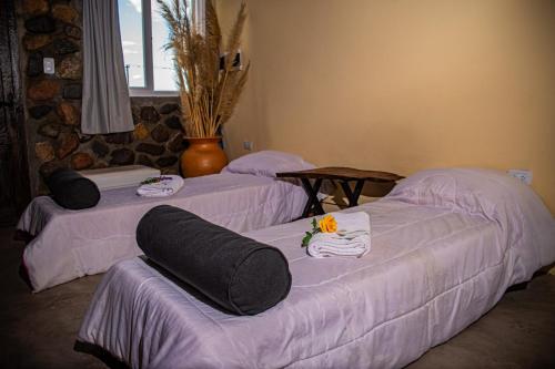 three beds in a room with towels on them at Cabañas 2Tierras in Chicoana