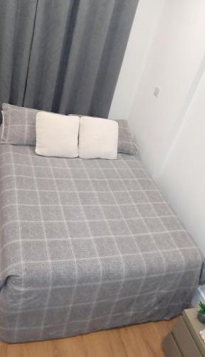 a gray bed with two pillows on top of it at Espaço Realeza in London