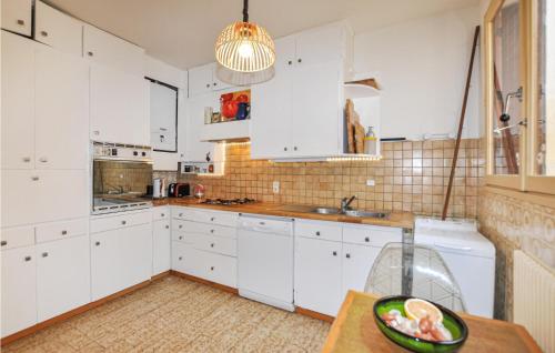 - une cuisine avec des placards blancs et un bol de fruits sur une table dans l'établissement Lovely Home In Sainte-Marie-La-Mer, à Sainte-Marie-la-Mer