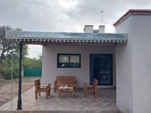 a patio with two wooden chairs and a table at Altos de Las Sierras in Cosquín