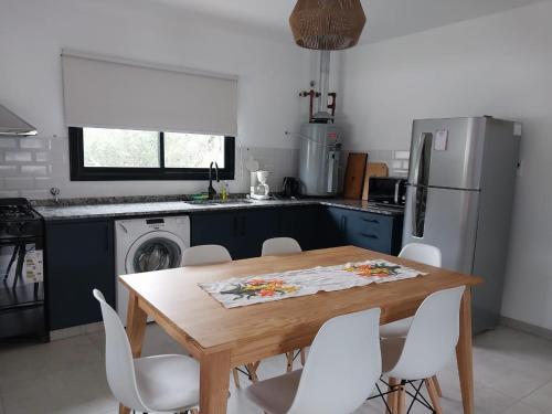 a kitchen with a wooden table and white chairs at Altos de Las Sierras in Cosquín