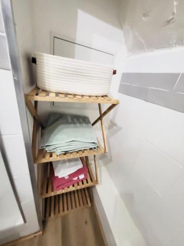 - un petit placard avec une étagère en bois et un panier dans l'établissement Charmant appartement au cœur du quartier St-Pierre, à Amiens