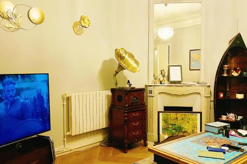 un salon avec une télévision et une cheminée dans l'établissement Élysées Charm, à Paris