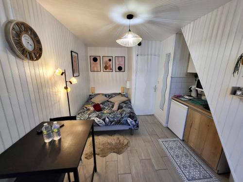 - une chambre avec un lit, une table et une horloge dans l'établissement Studio cosy au cœur du quartier Saint-Pierre, à Amiens