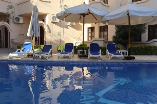 a group of chairs and umbrellas next to a pool at El Nakhil Hotel in Luxor