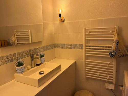 une salle de bain blanche avec un lavabo et un miroir dans l'établissement Appartement cosy, à Saintes-Maries-de-la-Mer