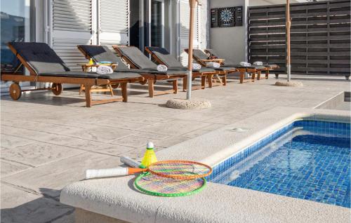 a pool with lounge chairs and a tennis racket next to it at Gorgeous Home In Srinjine in Srinjine