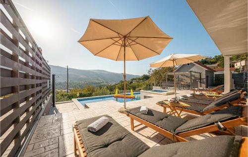 a patio with chairs and an umbrella and a pool at Gorgeous Home In Srinjine in Srinjine