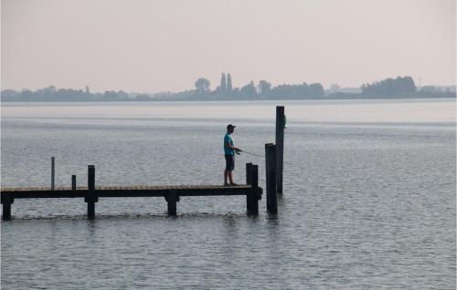 a man standing on a dock in the water at Nice Ship In Biddinghuizen With Kitchen in Biddinghuizen