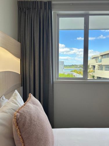 a bedroom with a bed and a large window at CitySide Hotel Tauranga in Tauranga