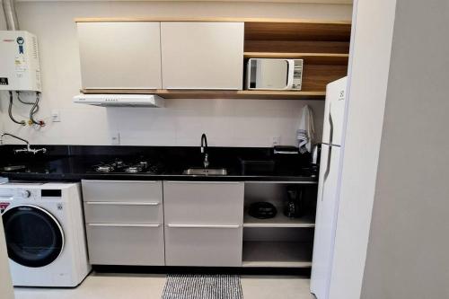 a small kitchen with a sink and a microwave at Apartamento aconchegante próximo Maria Fumaça in Bento Gonçalves