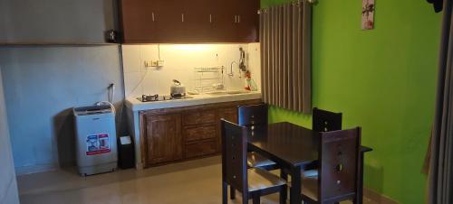 a kitchen with a table and a green wall at 3 Bedroom Fully Furnished LC Home in Singaraja
