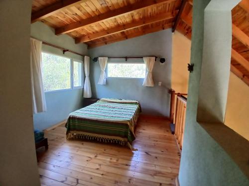 Un dormitorio con una cama en una habitación con ventanas. en El Jardin de Sauce, en Monte Hermoso