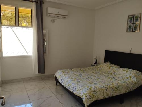 a bedroom with a bed and a large window at Charmante maison Riviera Golf Jardins in Abidjan